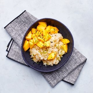 Bowl of mango sticky rice topped with black sesame seeds and scallions