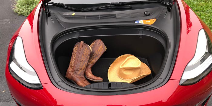 Red Tesla Model 3 with frunk open and a pair of boots and a yellow cloth inside.