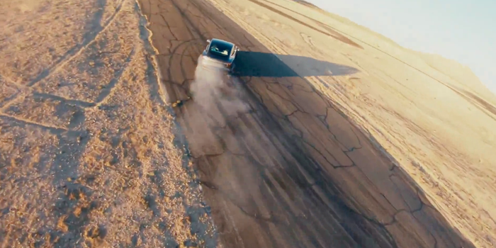 Tesla driving on asphalt in desert in Track Mode